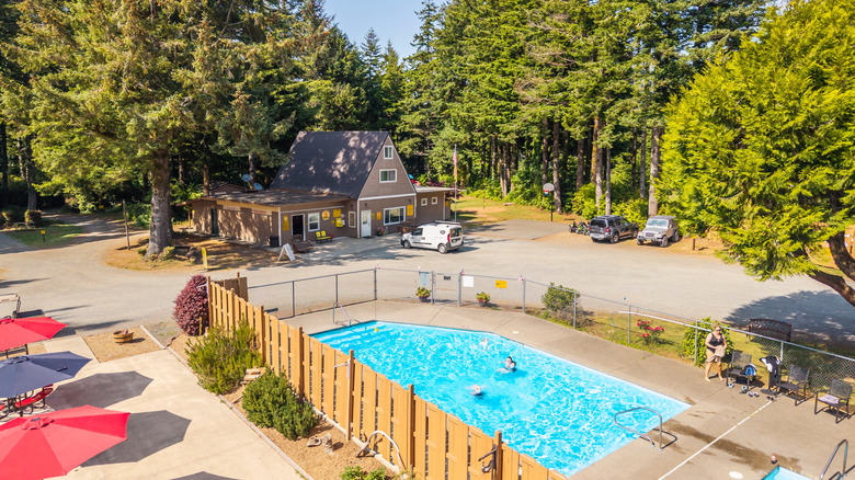 A KOA campground with a large swimming pool surrounded by pine trees.
