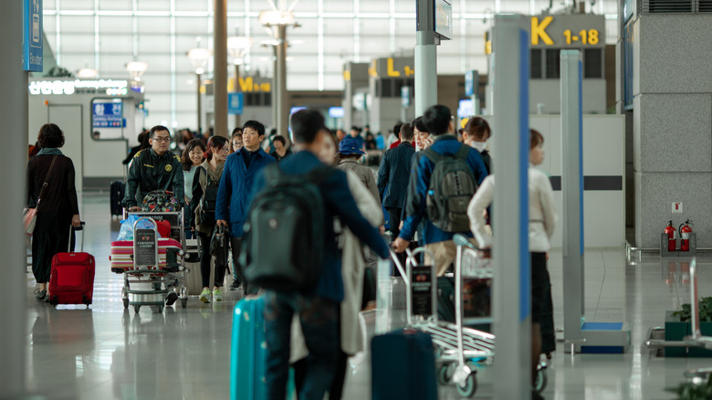 Passengers walking along an airport corridor next to the check-in counters