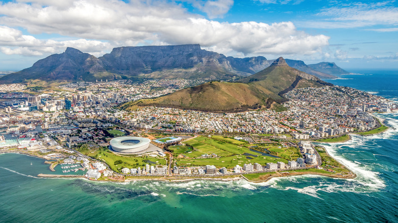 An arial view of Cape Town with mountains in the distance and waves crashing around the cliffs.