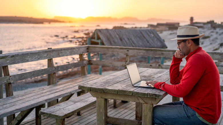digital nomad working on a beach at sunset