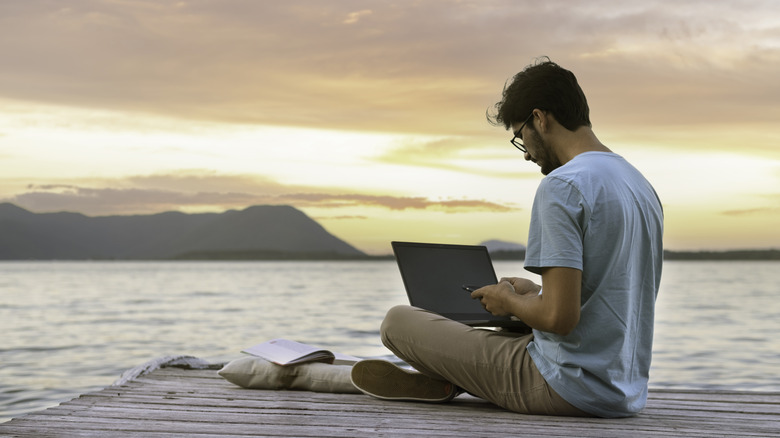 digital nomad doing some work on the edge of a body of water