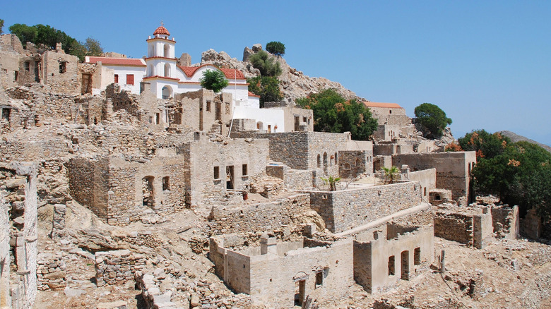 Stone ruins and whitewashed church in abandoned village