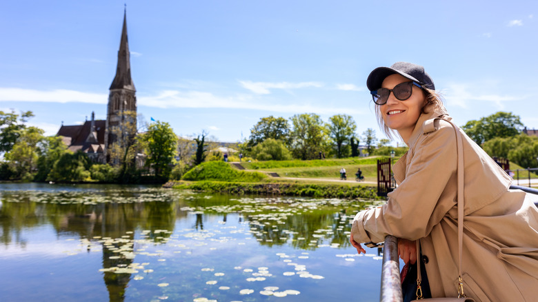 Woman smiling outside Kastellet citadel park against St. Alban's Church in Churchill park, Copenhagen, Denmark