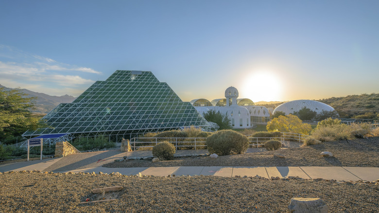 Biosphere 2 research facility with greenhouses and sky with sun setting