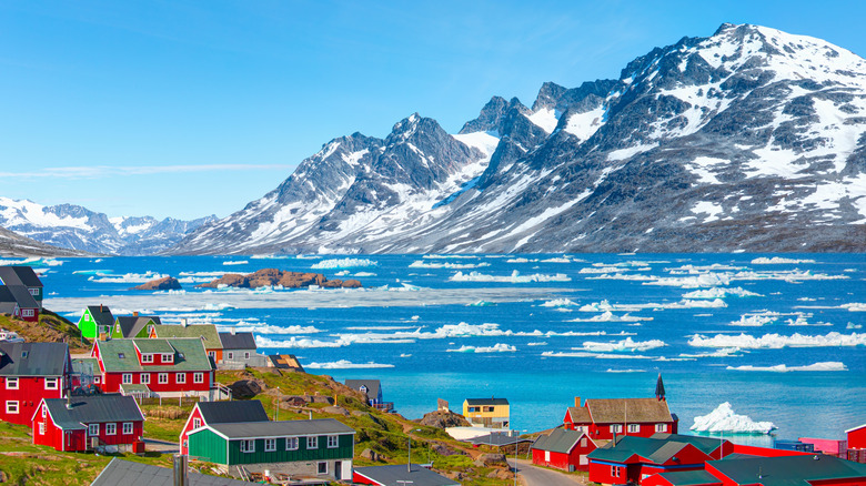 View of the colorful houses, ice-covered sea, and dramatic mountains in Tasiilaq, East Greenland