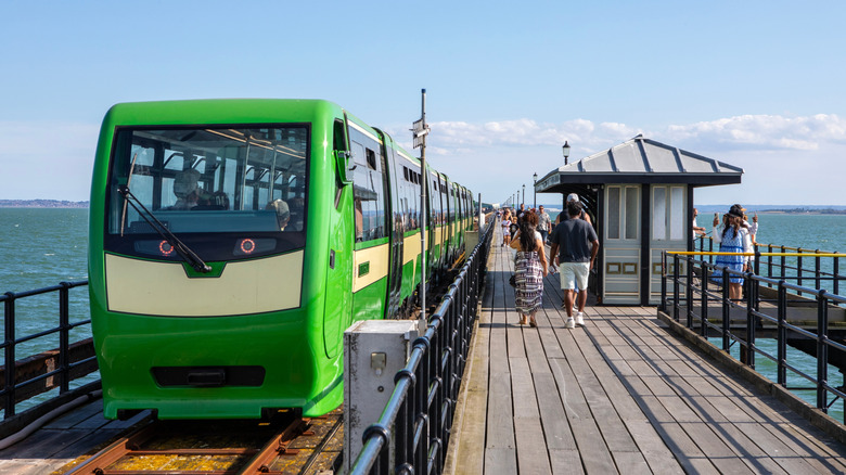Southend Pier Railway in action while others walk beside it on Southend Pier in Southend-on-the-Sea, UK