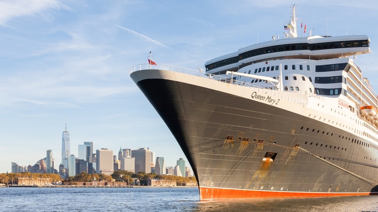 Daytime image of the Queen Mary 2, a luxury ocean cruise liner, with the iconic New York cityscape in the background