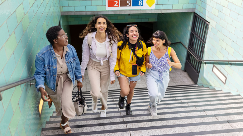 Four women climbing the stairs out of a metro station.