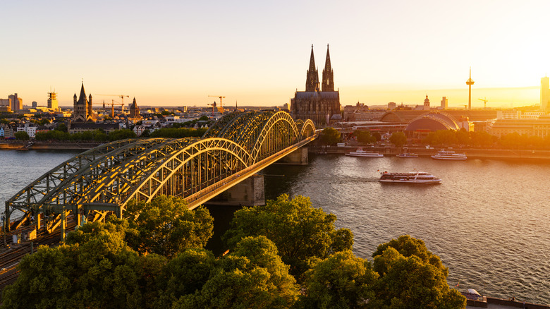 Aerial view of the skyline and bridge of Cologne, Germany and the Rhine River, with boats cruising by, pictured around sunset