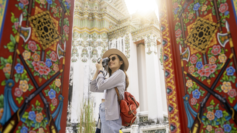 A female tourist takes pictures in a colorful temple complex in Bangkok's Wat Pho.