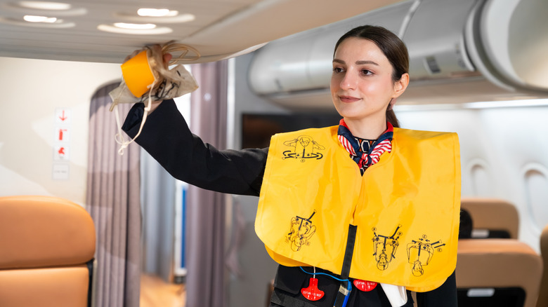 A flight attendant provides a safety demonstration inside a plane