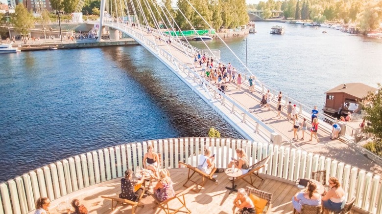 People dining on a terrace and walking on bridge in Tampere, Finland