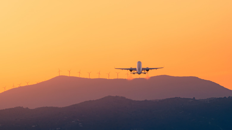 A plane taking off as the sun sets.