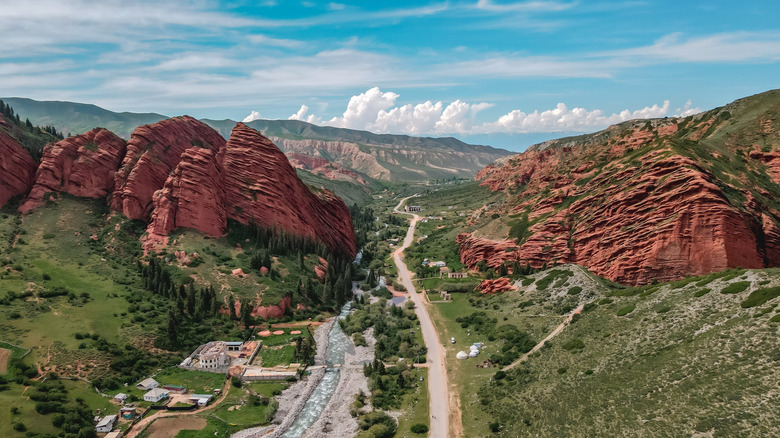 road and river through large red rocks in Kyrgyzstan
