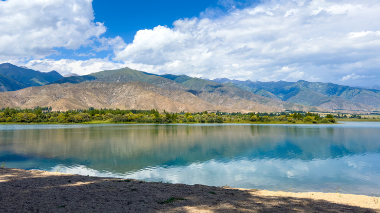 A photo of the calm lake surface on a sunny day reflecting the mountains