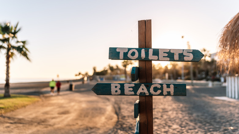 Wooden sign marking the direction of the toilets and the beach