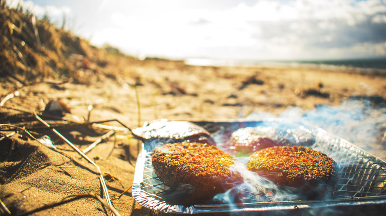 Barbecue on the beach smoking with single use charcoal barbecue