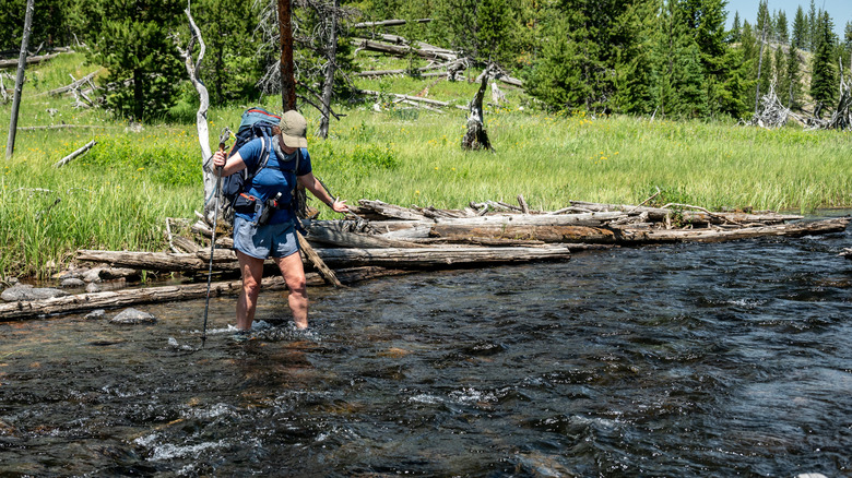 A backpacker fords a river in Yellowstone National Park