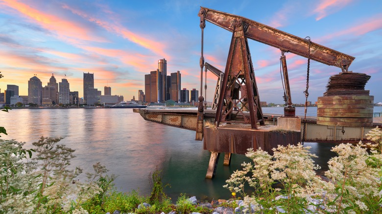 Rusting industrial machinery on a lake with the Detroit skyline in background at sunset