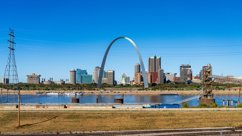 Skyline view of St Louis featuring its landmark arch with railroad and industrial tower in the foreground