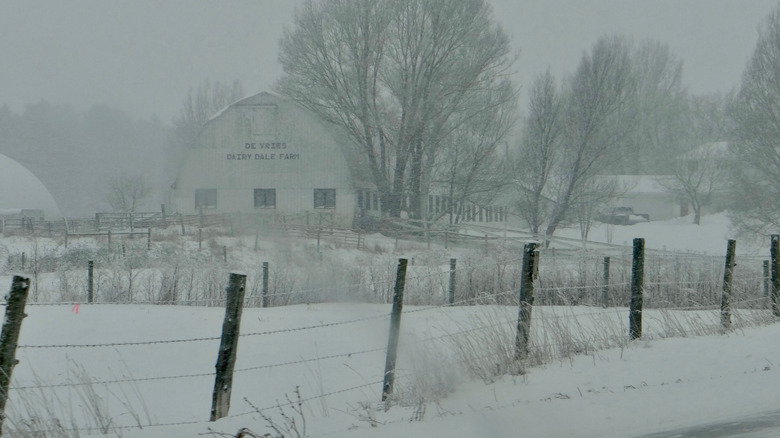A barn and wooden fence during a snowstorm in Vermont