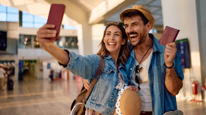Happy couple takes selfie with passport at airport