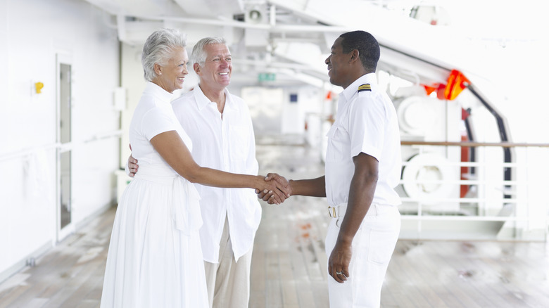 Crew member shaking woman's hand on a cruise ship deck