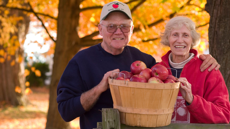 Two seniors pose with a bushel of apples in Vermont