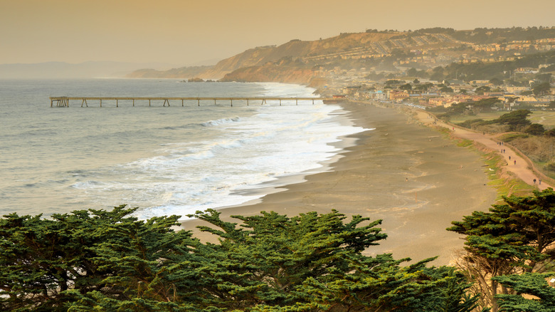 Pacifica Pier extends into the ocean from the sandy beach in Pacifica, California.