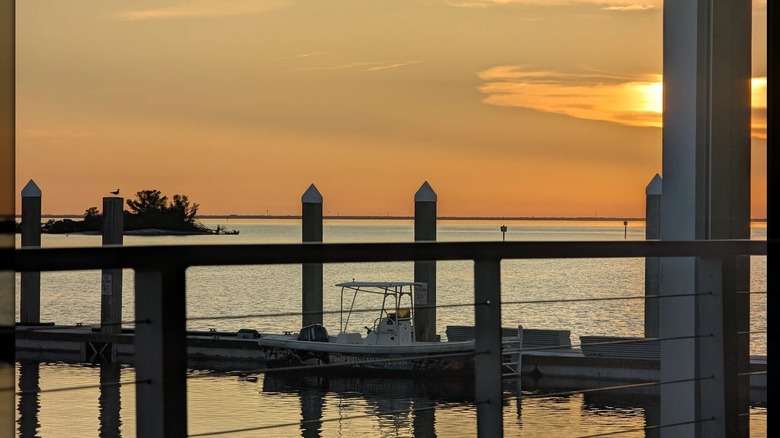 Hula Bay's pier with one boat boat docked as seen from the back patio, as the sun sets