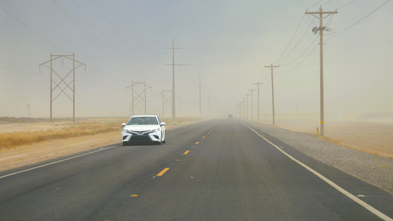 Phoenix, Arizona - A car drives through a summer dusty sand storm with low visibility along a rural desert road.