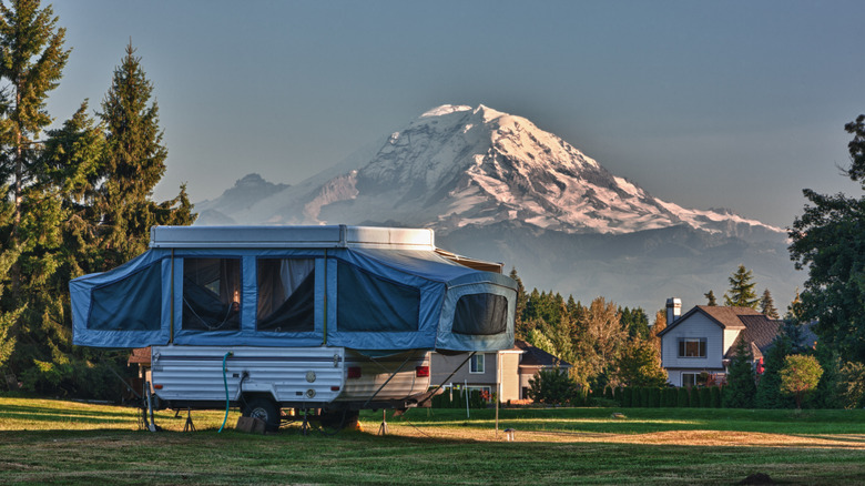 Popup camper trailer parked in yard with mountain view