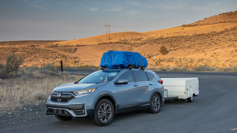 Car with items on roof towing a pop-up camper trailer