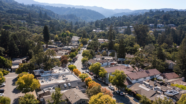 A winding road curves through Saratoga, with mountains in the background