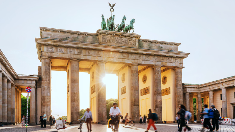 People walk by Berlin's Brandenburg Gate in the morning