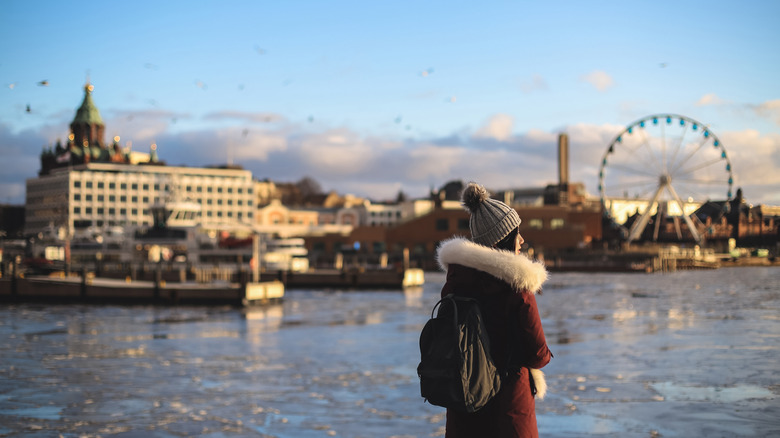 Woman in coat with fur overlooks the skyline of Helsinki in winter