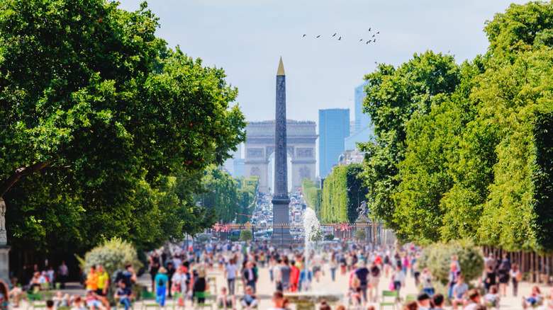 Crowds of people walk towards the Arc d'Triomphe on the Champs-Elysee in Paris