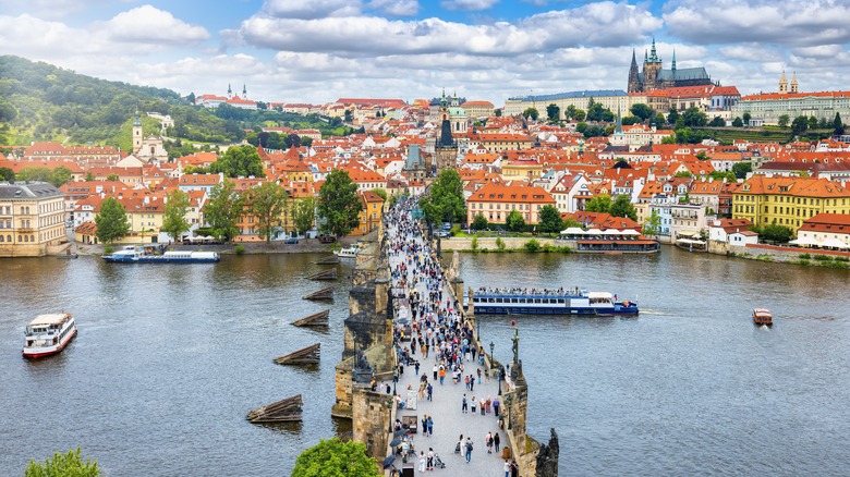 Aerial view of the Charles Bridge in Prague, full of people, and the Prague skyline