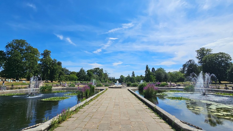 View of  a cobblestone walkway flanked by lily ponds at the Italian Gardens at London's Kensington Gardens