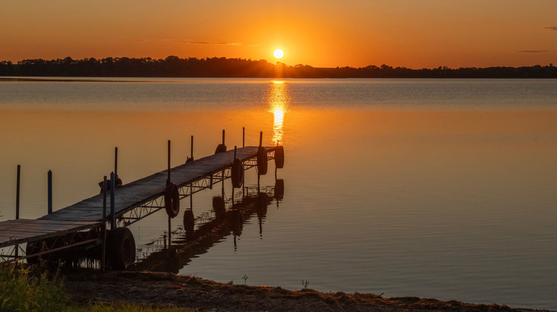 Sunset over Ten Mile Lake in Minnesota with a wooden dock in the foreground.