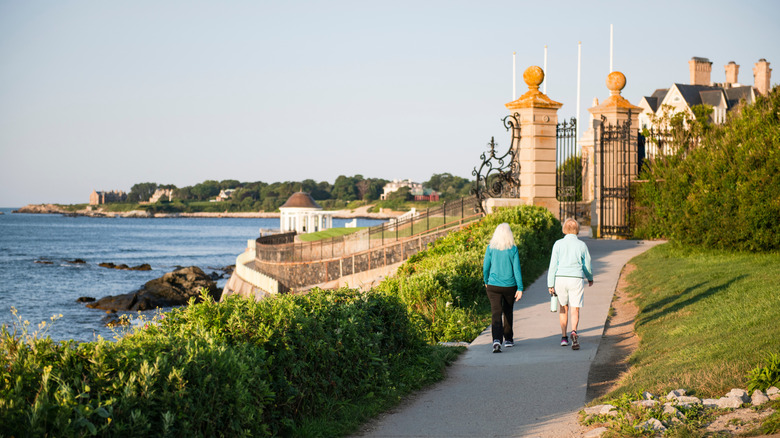 A couple strolling along the Cliff Walk in Newport, Rhode Island, on a sunny day