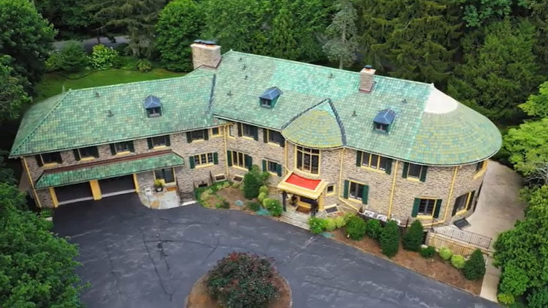 Stone-walled estate with a green roof in Merion Station, surrounded by trees and grass