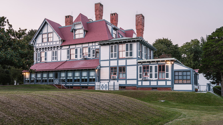 Mansion in Philadelphia, a large white-walled building with a red roof and multiple chimneys surrounded by grass and trees