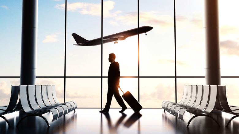 Person walking through an airport with a suitcase