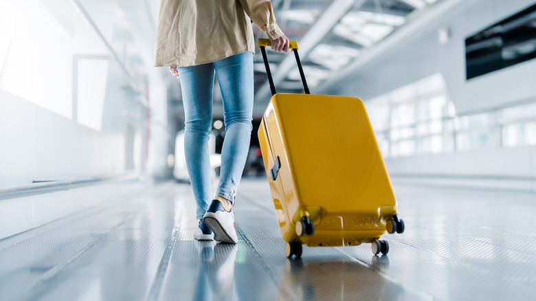Someone walking through an airport with a suitcase