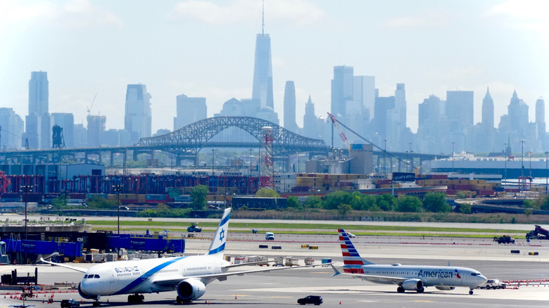 The New York City skyline lines the background with the Newark Airport tarmac in the foreground with two airplanes
