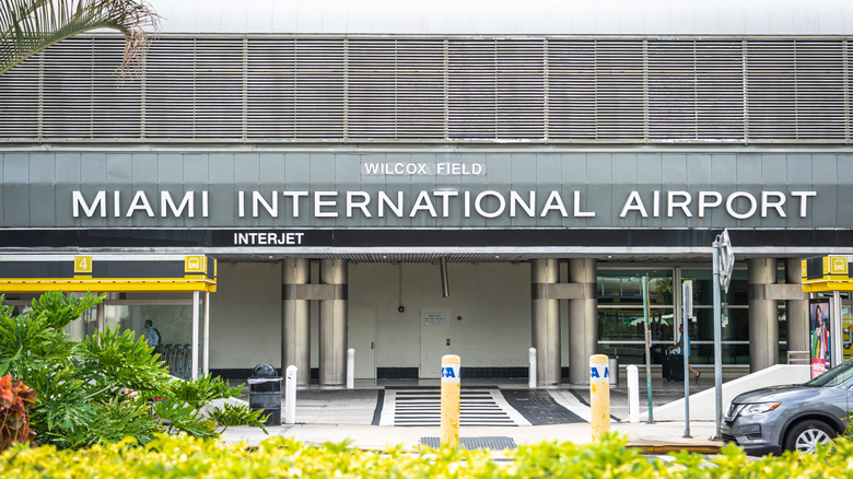 Image of the drop off lane at the front of the Miami International Airport with its name on the overhang out front
