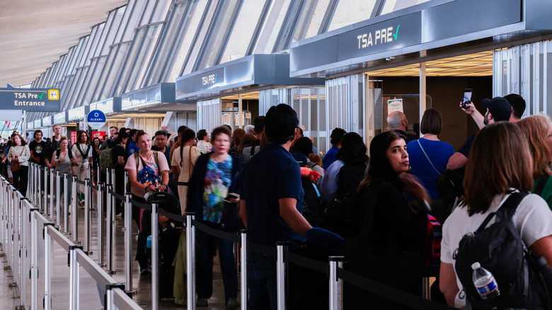 a large group of travelers wait in a long line to enter the security checkpoint
