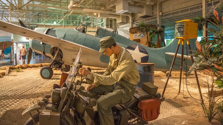 A display of an American marine on a motorcycle next to a Grumman F4F-3 Wildcat Fighter at the Pearl Harbor Aviation Museum.