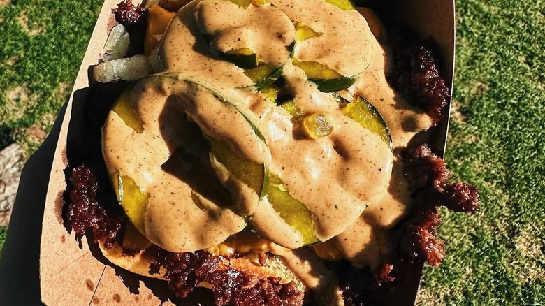 close-up of open-faced Love Hour smash burger with pickles and sauce